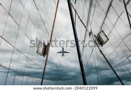 Airplane. The plane flies over high-rise modern buildings against the background of a blue dark sky with clouds and clouds.