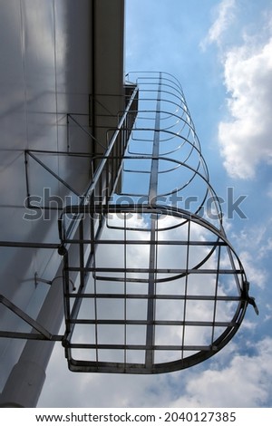 Aluminium cat ladder with cage. Outdoor fire escape, It is installed on the side of the building in the bottom view. Fire escape stairs outside the building.