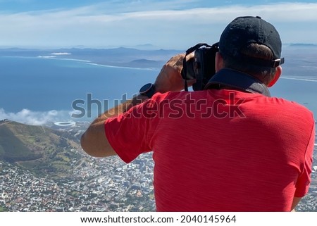 Man in red shirt taking pictures of Cape Town, South Africa from top of Table Mountain