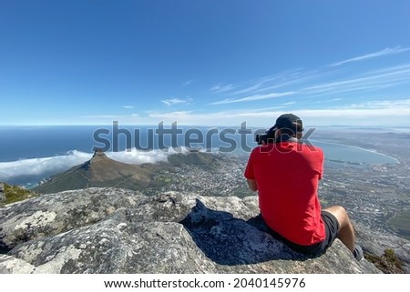 Man in red shirt taking pictures of Cape Town, South Africa from top of Table Mountain