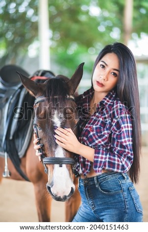 A young Asian Thai woman is standing with a horse.