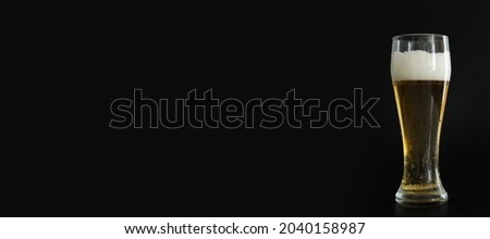 Frosty glass of cold golden beer with bubbles on the black background. Free space for text, copy space, banner. Drinking alcohol on party, holidays, Oktoberfest or St. Patrick's Day.