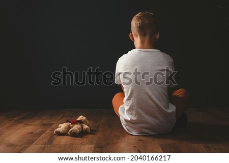 the boy is sitting alone in the room. harassment of kid. bullying of children Royalty-Free Stock Photo #2040166217
