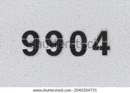 Black Number 9904 on the white wall. Spray paint. Number nine thousand nine hundred four.