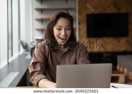 Excited millennial woman look at laptop screen shocked by unexpected good online sale offer or promotion discount. Smiling young female feel euphoric triumph with promotion news online on computer. Royalty-Free Stock Photo #2040223601