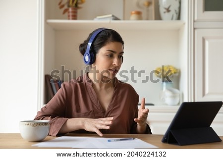 Confident young biracial female freelance specialist consult client from home by videocall using tablet pc headphones. Busy indian lady discuss terms conditions of documents meeting with lawyer online Royalty-Free Stock Photo #2040224132