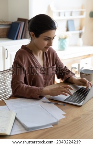 Freelance job. Vertical photo of millennial indian female work on laptop computer at home office. Focused young mixed race woman remote employee student type report on pc keyboard learn subject online Royalty-Free Stock Photo #2040224219