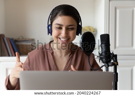 Giving voice to story. Talented indian female professional reader narrator in wireless headset record audio book using special equipment condenser microphone pop filter and sound editing app on laptop Royalty-Free Stock Photo #2040224267