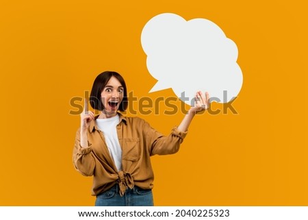 Wow idea concept. Surprised woman holding blank speech bubble and finger up, space with mockup for ad design over yellow studio background. Lady showing empty word box, free space