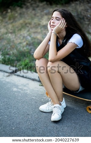 Young girl teenager is posing with her longboard (skate board) outdoor in a park. May be a concept of youth, teenagers, teenage sports