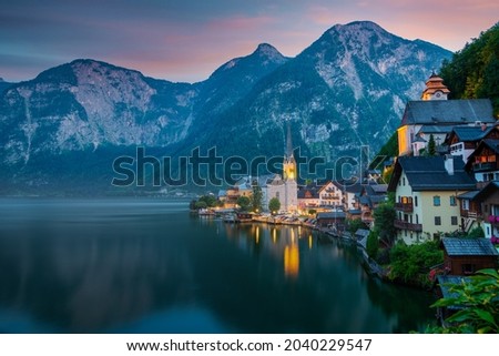 Hallstatt, Austria - A scenic picture postcard view of the famous village of Hallstatt reflecting in Hallstattersee lake in the Austrian Alps at dusk.