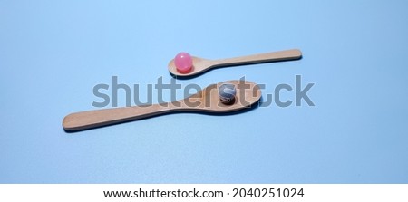 Two wooden spoons with marbles on them on a blue background. Collection of creative Backgrounds.