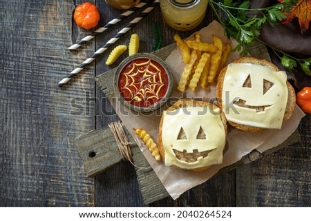Halloween party food. Halloween party fun ghost burger, ketup sauce and  potatoes frie on a wooden table. Top view flat lay background. Copy space.