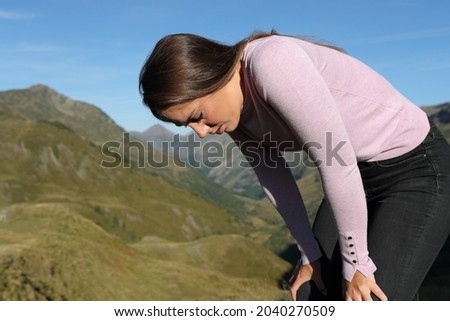 Exhausted casual woman resting after walking in the mountain Royalty-Free Stock Photo #2040270509