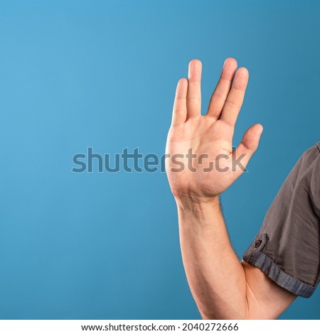 male hand doing scifi greeting on a blue background