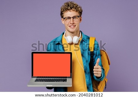 Young boy teen student in casual clothes backpack glasses hold work laptop computer blank screen workspace show thumb up isolated on violet background studio Education in university college concept Royalty-Free Stock Photo #2040281012