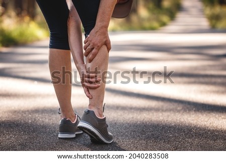Woman feeling pain of her legs during jogging. Calf muscle cramp. Underestimating the warm-up exercise before running Royalty-Free Stock Photo #2040283508
