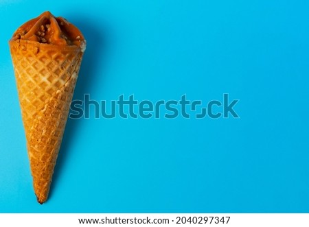 Flat lay of cone caramel ice cream on blue bright background.