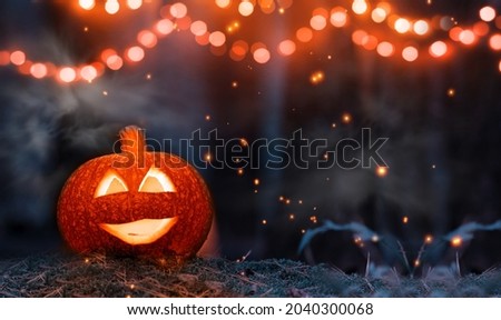 Jack o lanterns glowing with moonlight in night forest. Halloween dark background with burning orange pumpkins on the ground with moss.Happy Halloween celebration card with decorations and smoke.  Royalty-Free Stock Photo #2040300068