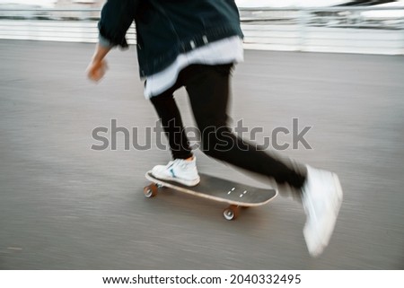 A blurry photo in motion. A freelancer rides a skateboard in the city. A young hipster man and his hobbies.