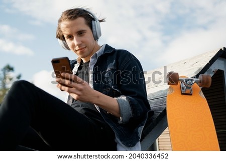 A young hipster man listens to music with headphones. A teenager responds to friends in a message on a smartwatch social network. The freelancer is stylish in a hat in the city.