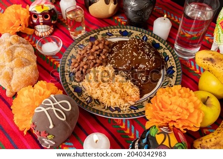 top view of an ofrenda with traditional Mexican food, alfeñique candies, fruit, candles, flowers and chocolate skulls for the Day of the Dead. Royalty-Free Stock Photo #2040342983
