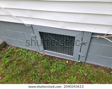 An old door at the bottom frame of a house. The small, hidden door leads to the cellar and crawl space below the house. Royalty-Free Stock Photo #2040343613