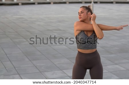 Close up of a young woman warm up her body by stretching her arms to be ready for exercising and do yoga. Outdoor workout exercise concept, copy space