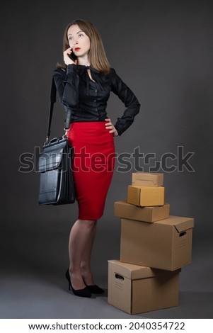 Small business executive. Businesswoman owner with phone. Businesswoman with boxes. Vertical portrait of woman business owner. Girl is talking to someone. Cardboard boxes as symbol of small business
