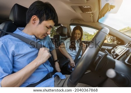 young couple fastening seat belt on before driving a car. Royalty-Free Stock Photo #2040367868