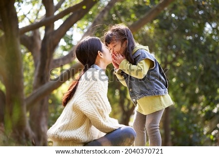 asian mother and daughter having a good time outdoors in city park