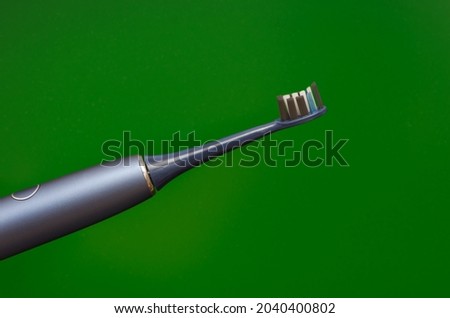 ultrasonic toothbrush blue, daily oral hygiene. Green background.