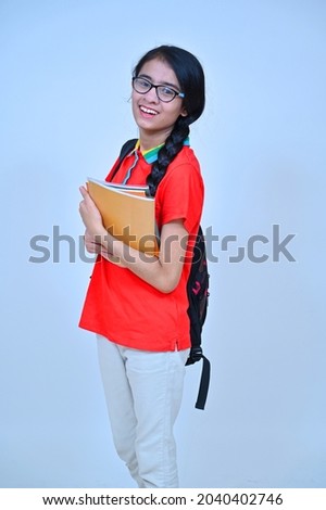 Teena age girl holding book and school bag , studio shot