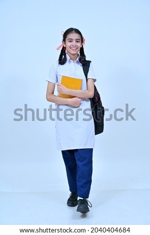 Village teenage girl in school uniform holding books and school bag, studio shot Royalty-Free Stock Photo #2040404684