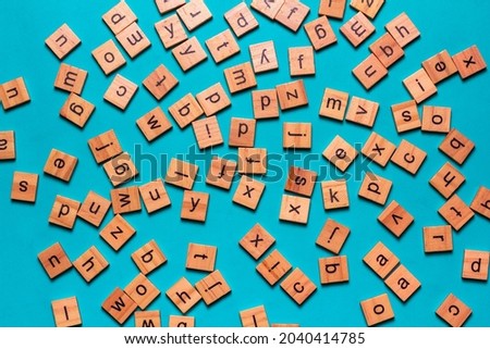 English alphabet made of square wooden tiles with the English alphabet scattered on blue background. The concept of thinking development,grammar.