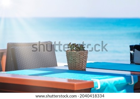 Good morning! potted flower on table with sun and defocused natural turquoise sea background
