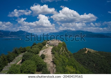 Fortress with a cross on a hill in the background Lake Garda. Fortress Rocca di Manerba aerial view. Panorama on the rocca di manerba top view. Lake Garda, Italy aerial view.