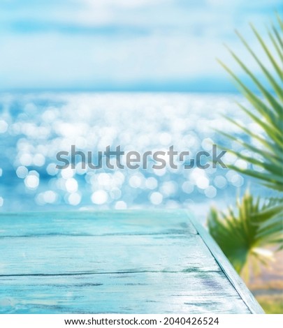 Blue wooden board and blurred sparkling sea at the background. It is possible to place your product. Summer holiday concept.