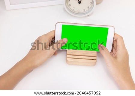 Close-up woman of Left hand and right hand held, use finger touches with digital smartphone green screen isolated on white background. Concept of technology, connection, communication, social.