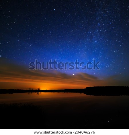 Morning dawn on a starry background sky reflected in the water of the lake.