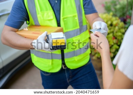 close-up photo of delivery man accept credit card from customer who pays delivery man with credit card and wireless POS machine for card payment