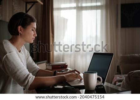 Smiling young asian woman video calling on laptop. Back view photo student looking at computer screen watching webinar or doing video chat by webcam. Over shoulder close up mock up screen view.