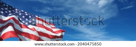 USA flag on a background of blue sky. National holidays concept Royalty-Free Stock Photo #2040475850