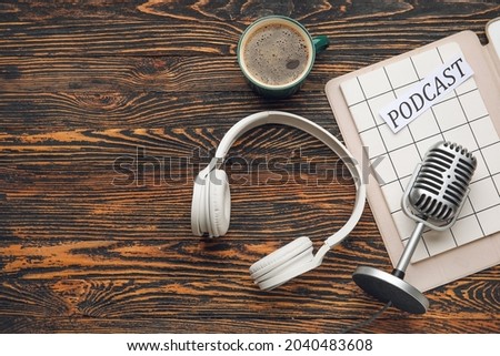 Retro microphone, headphones, paper with word PODCAST and cup of coffee on wooden background