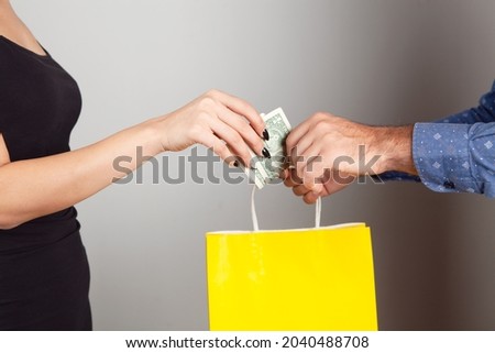 a man gives a gift bag and a woman pays for it. shopping concept