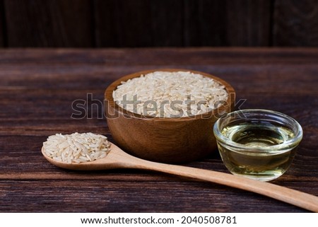 Rice bran oil extract and brown rice on wood table background. Royalty-Free Stock Photo #2040508781
