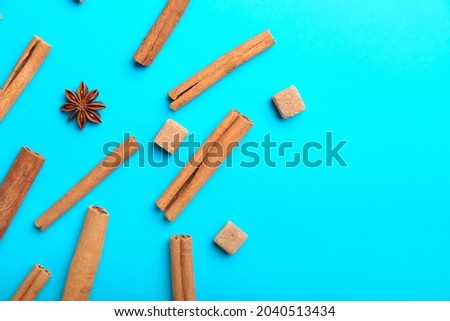 Cinnamon sticks, sugar and anise on color background