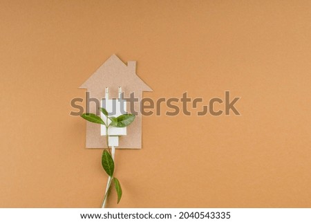 Flat lay cardboard house, electrical plug, leaves. Save energy concept. copy space. High quality photo