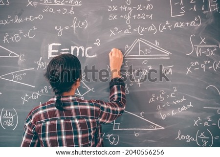 Teacher or student writing on blackboard during lesson and lecture in school classroom.