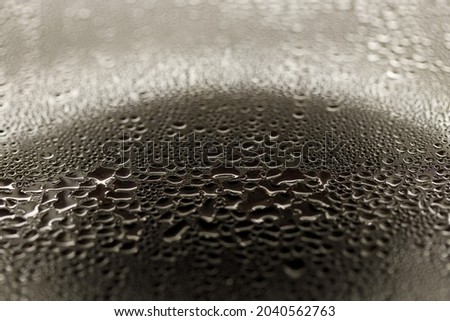 Drops on glass. Texture for designer background. Drops of water flow down the surface of the clear glass on a black background. Raindrops for overlaying on window. Concept of autumn weather.